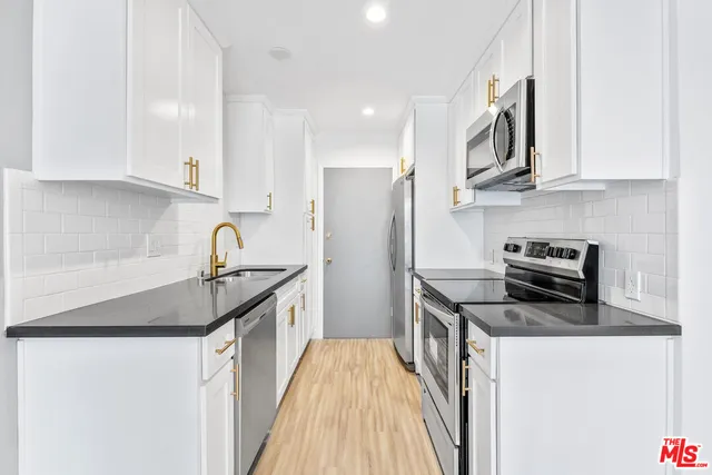 a kitchen with stainless steel appliances granite countertop a sink stove and refrigerator