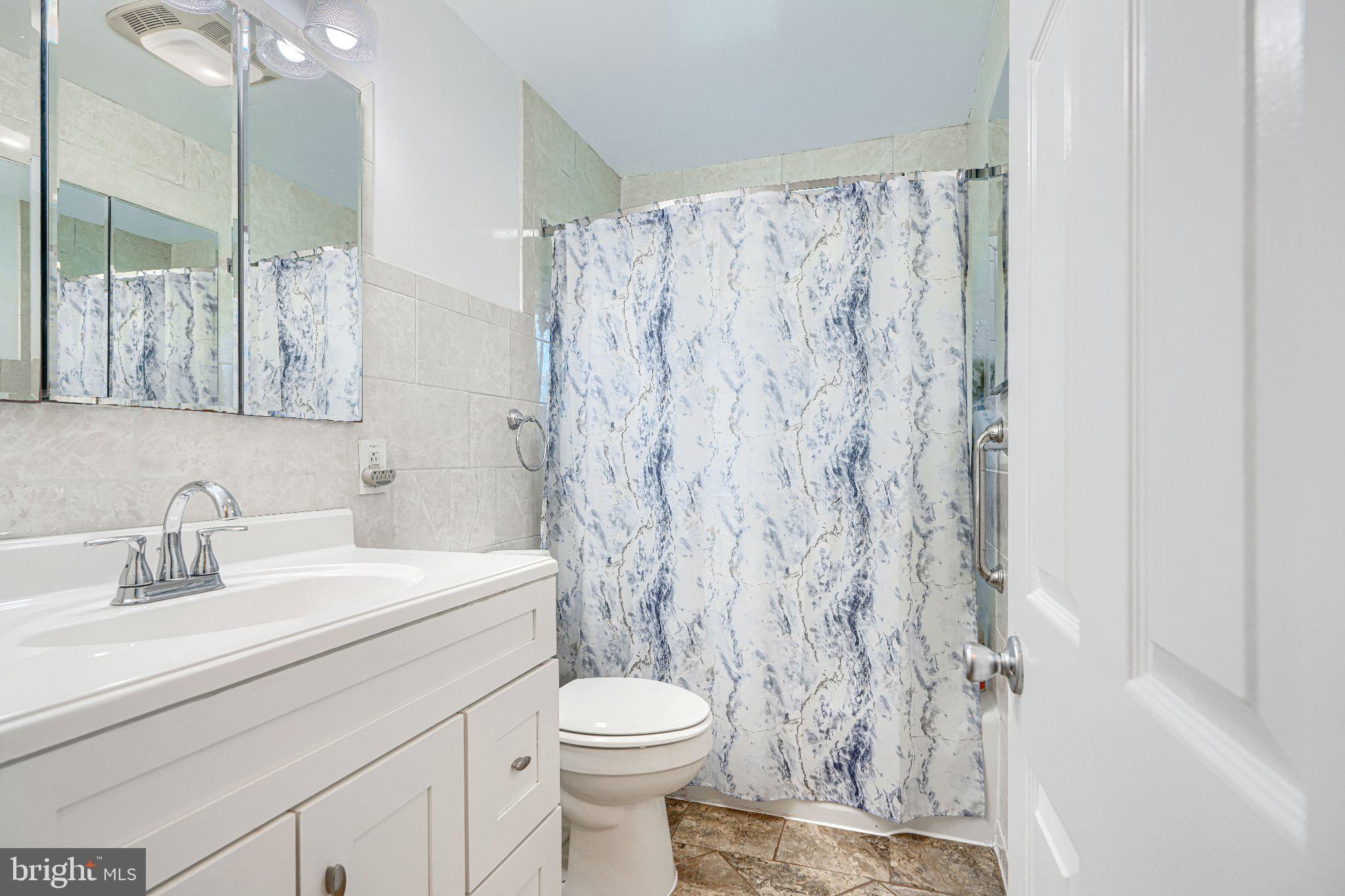 1234 St Andrews Way Baltimore, MD 21239 - Photo 37 of 38 a bathroom with a sink a toilet and shower curtain