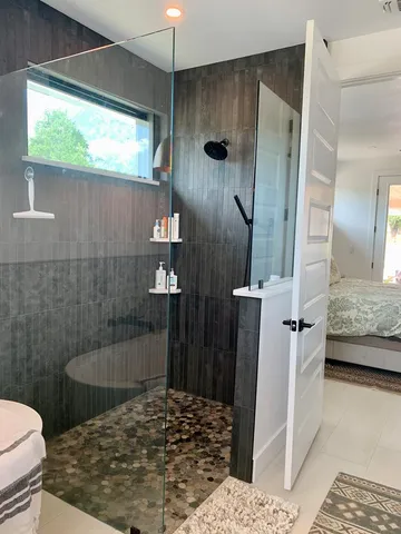 a bathroom with a sink a toilet a shower and a window