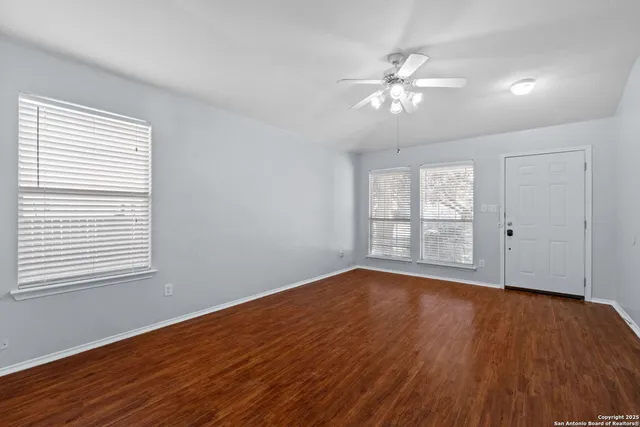 a view of empty room with wooden floor and fan