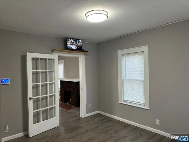 an empty room with wooden floor cabinet and windows