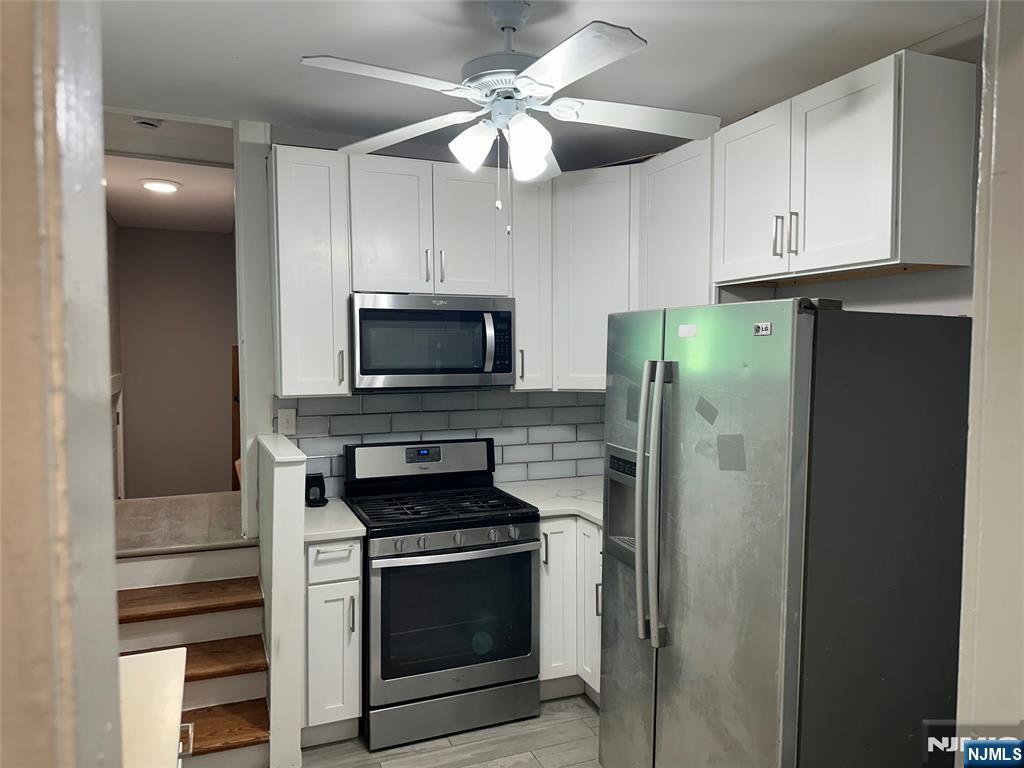 1041 Hunterdon Street Newark, NJ 07112 - Photo 7 of 25 a kitchen with stainless steel appliances white cabinets and a refrigerator