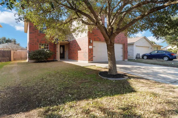 a front view of a house with a yard and large tree