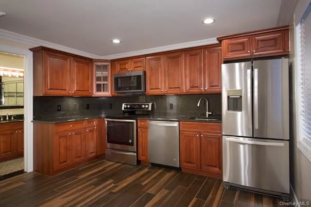 a kitchen with granite countertop wooden cabinets a refrigerator and a stove top oven