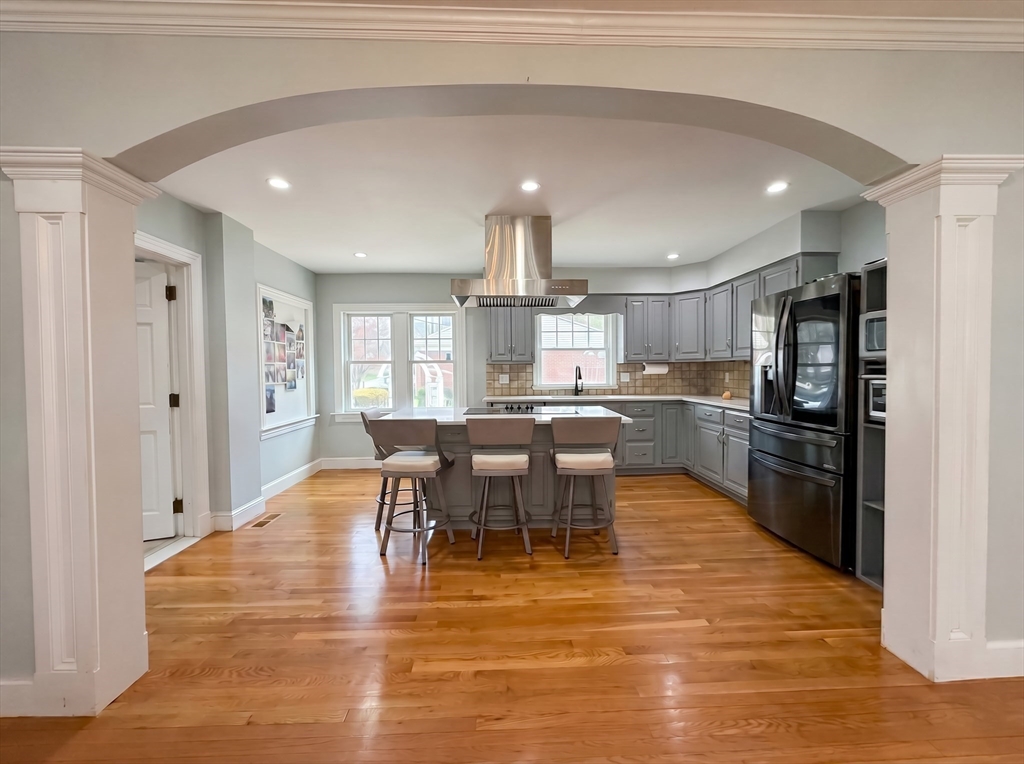 115 Hawthorn Road Braintree, MA 02184 - Photo 9 of 37 a kitchen with stainless steel appliances kitchen island granite countertop a refrigerator a stove a sink a dining table and chairs with wooden floor