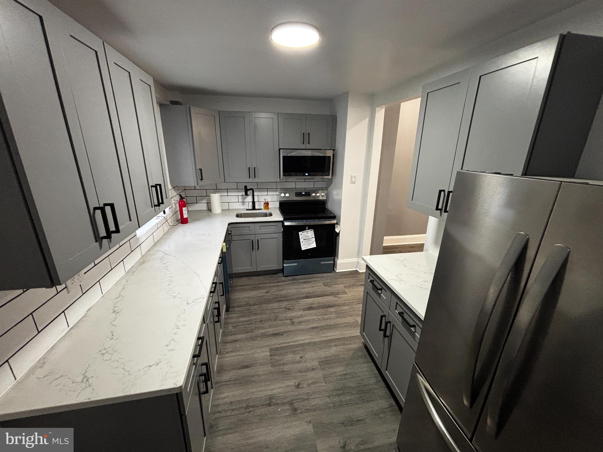 901 South 60th Street Philadelphia, PA 19143 - Photo 6 of 34 a large kitchen with a sink a refrigerator and a stove top oven