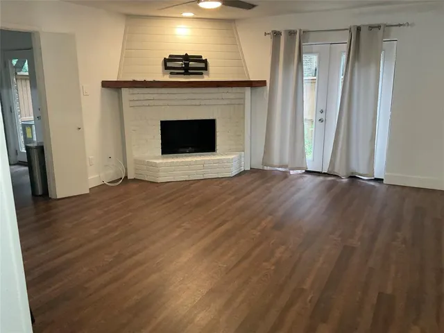 a view of an empty room with wooden floor and a fireplace