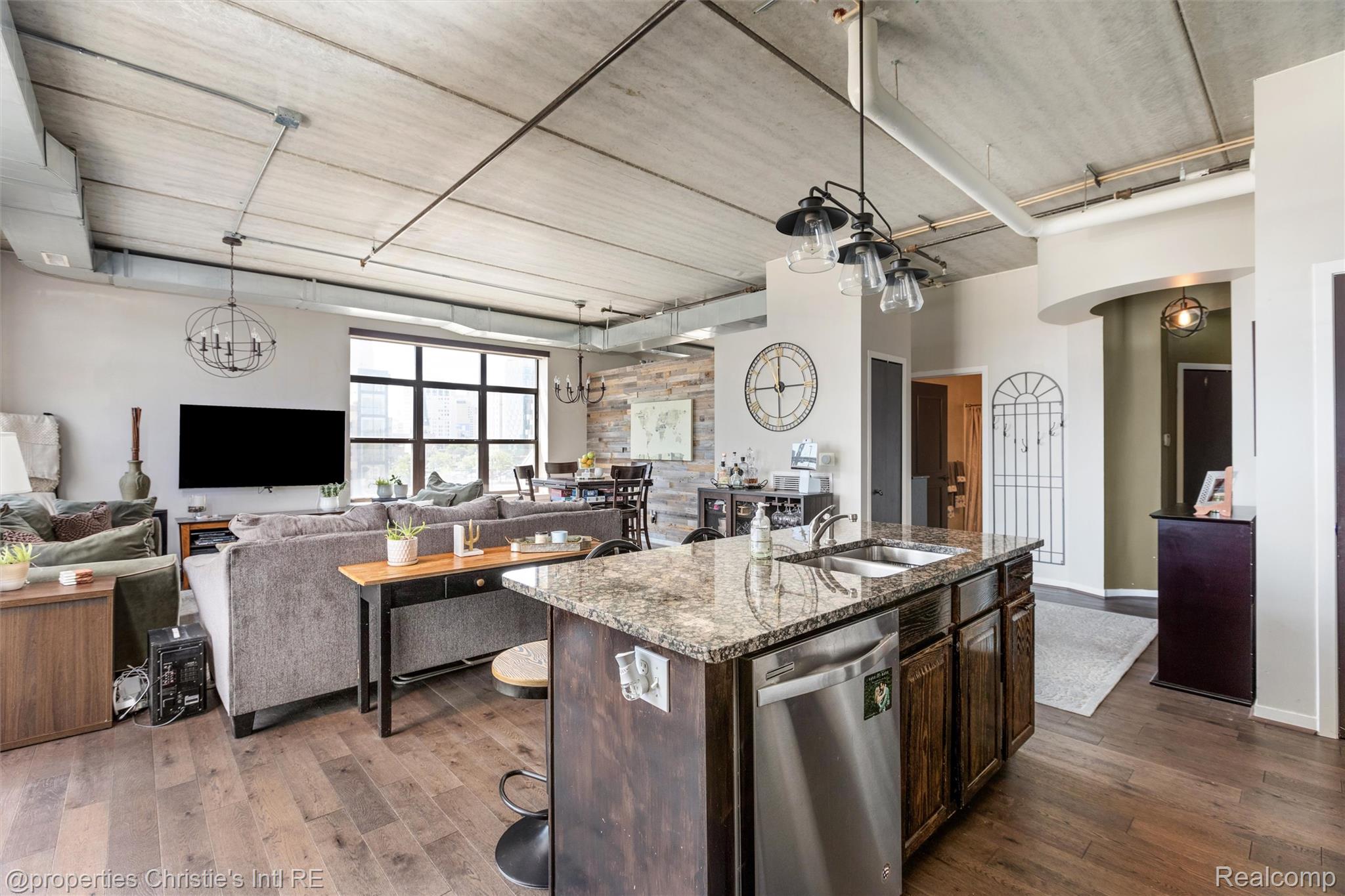 66 Winder Street, Unit 332 Detroit, MI 48201 - Photo 30 of 30 Kitchen featuring open floor plan, a center island with sink, light stone counters, stainless steel dishwasher, and dark wood finish cabinetry