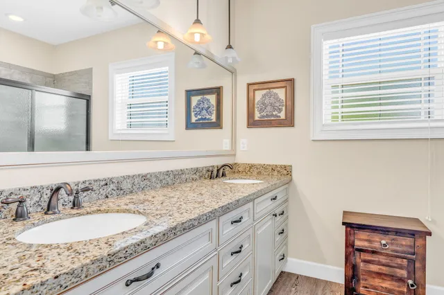 a bathroom with a granite countertop sink and a window