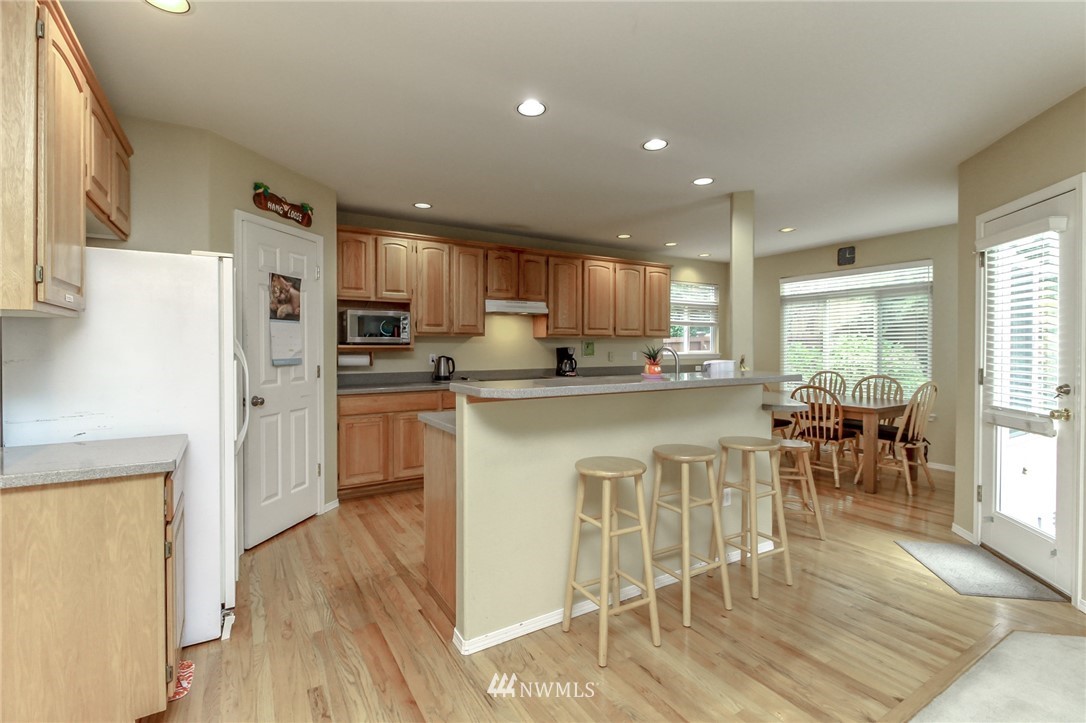 18547 173rd Way Southeast Renton, WA 98058 - Photo 11 of 27 a kitchen with stainless steel appliances granite countertop a refrigerator a stove top oven and a dining table with wooden floor
