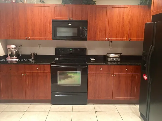 a kitchen with stainless steel appliances granite countertop wooden cabinets and a stove top oven