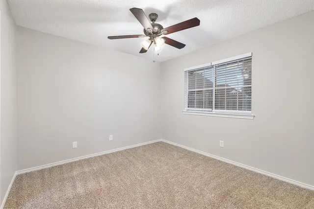 an empty room with ceiling fan and windows