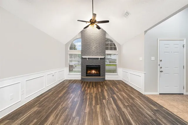 a view of an empty room with wooden floor fireplace and a window