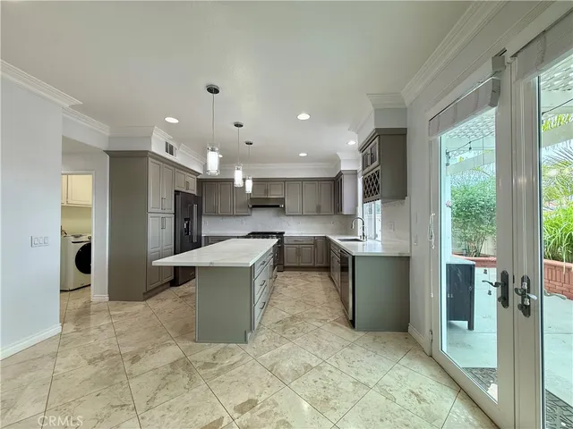 a large kitchen with stainless steel appliances kitchen island granite countertop a refrigerator and a sink