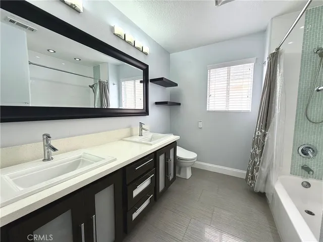 a bathroom with a double vanity sink a toilet and a bathtub