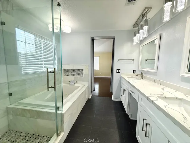 a spacious bathroom with a tub sink shower and mirror