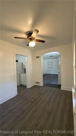 an empty room with wooden floor cabinet and windows