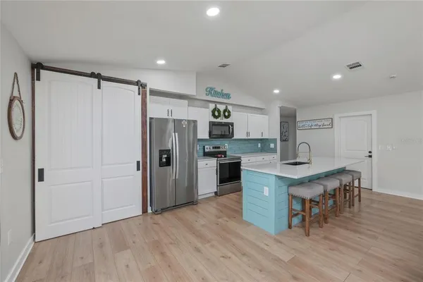 a kitchen with stainless steel appliances granite countertop a table chairs refrigerator and stove