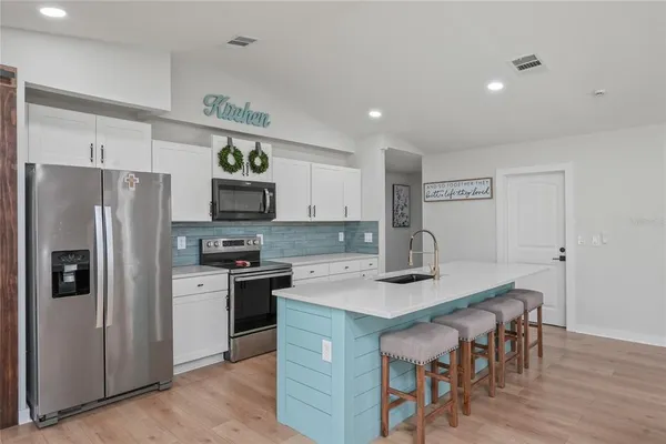 a large white kitchen with a sink and a stove top oven