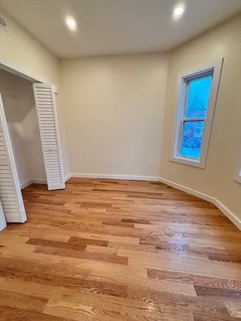 a view of an empty room with wooden floor and closet