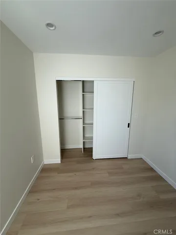 a view of an empty room with wooden floor and closet