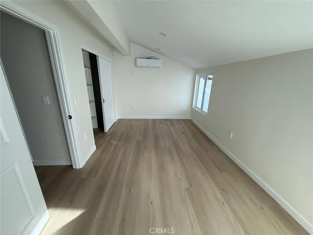 an empty room with wooden floor & closet and mirror