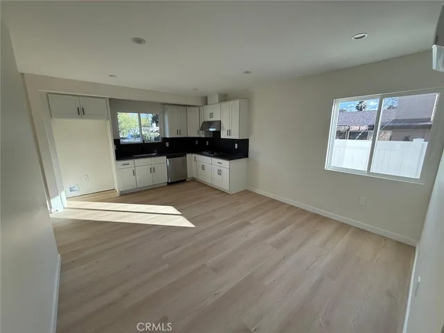 a kitchen with stainless steel appliances wooden floors and white walls