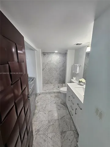 a spacious bedroom with a bed and large mirror next to a window