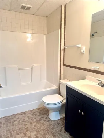 a bathroom with a granite countertop sink a toilet a mirror and bathtub
