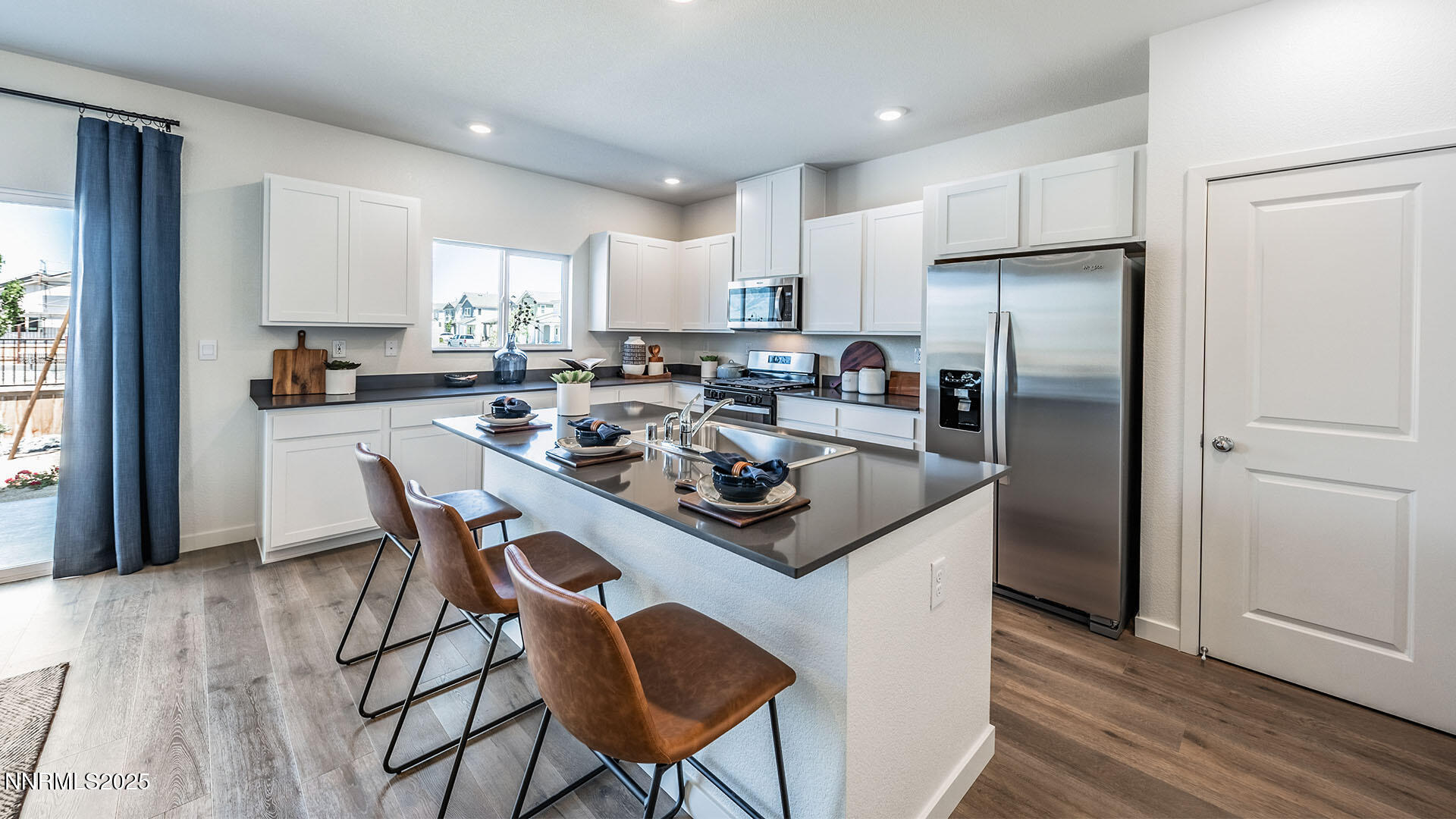 7836 Lazy Stream Drive, Unit 151 Reno, NV 89506 - Photo 5 of 25 a kitchen with stainless steel appliances a table chairs refrigerator and cabinets