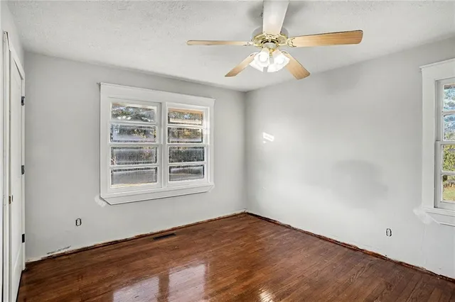 an empty room with windows and fan