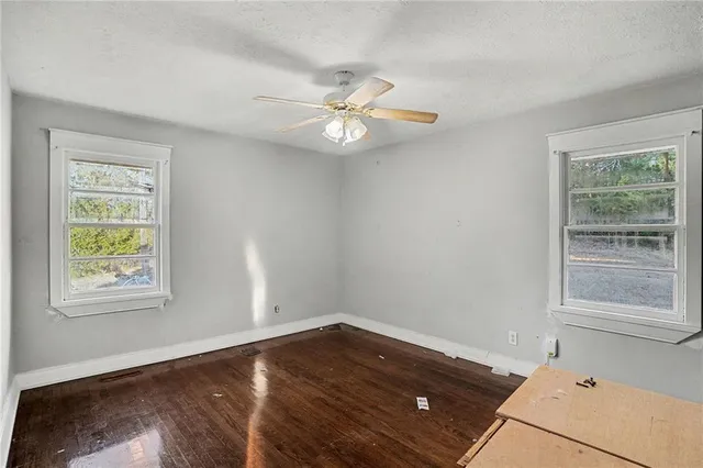a view of empty room with wooden floor and fan