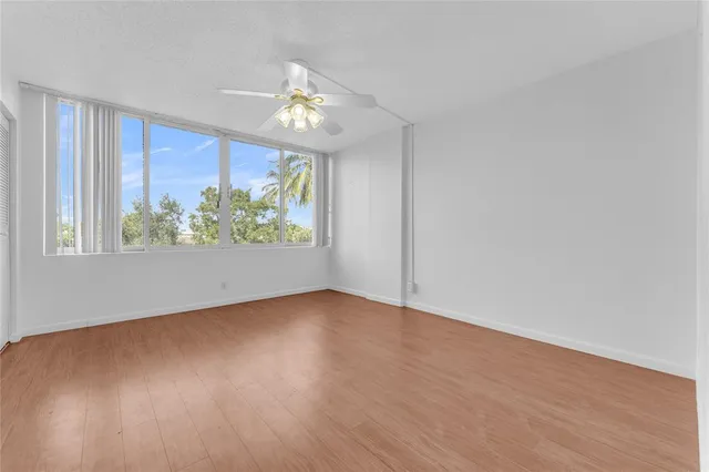 a view of an empty room with wooden floor and window