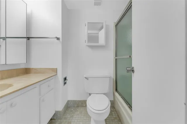 a bathroom with a granite countertop toilet and a sink