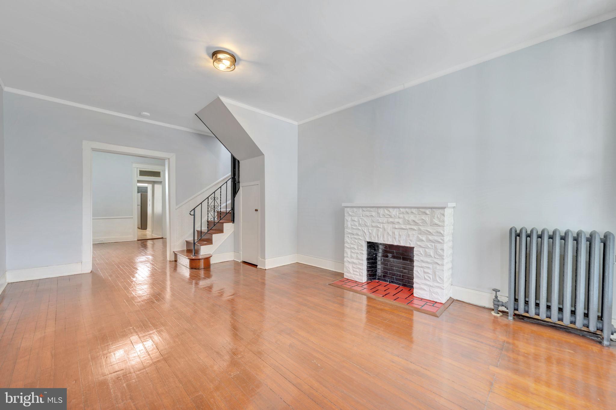 2822 Riggs Avenue Baltimore, MD 21216 - Photo 5 of 30 a view of an empty room with wooden floor fireplace and a window