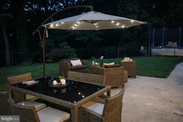 a view of a patio with a dining table and chairs under an umbrella with a fire pit and garden