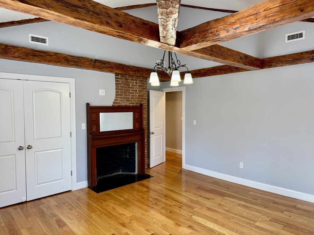 722 Lowell Street, Unit A Peabody, MA 01960 - Photo 13 of 40 a view of an empty room with wooden floor and a fireplace