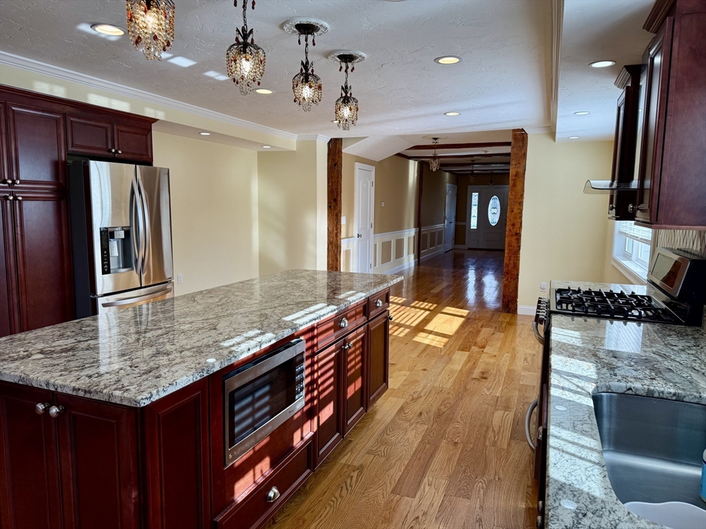722 Lowell Street, Unit A Peabody, MA 01960 - Photo 15 of 40 a kitchen with stainless steel appliances granite countertop a sink refrigerator and microwave