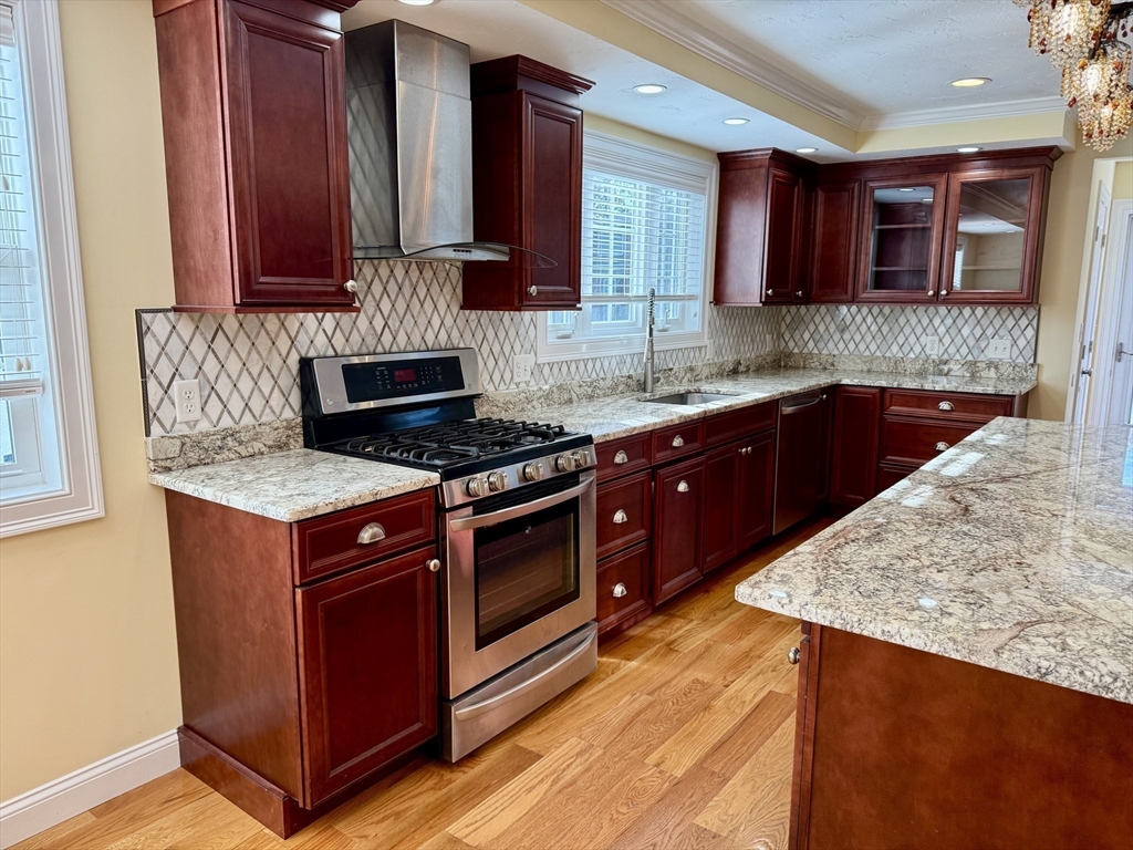 722 Lowell Street, Unit A Peabody, MA 01960 - Photo 17 of 40 a kitchen with stainless steel appliances granite countertop wooden cabinets and a stove top oven