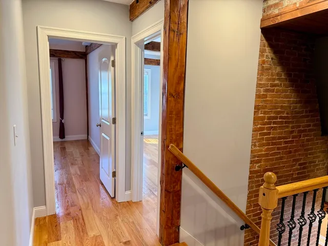 a view of a hallway with wooden floor and staircase