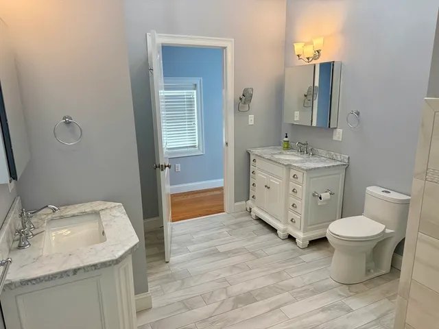 a bathroom with a granite countertop toilet sink and mirror