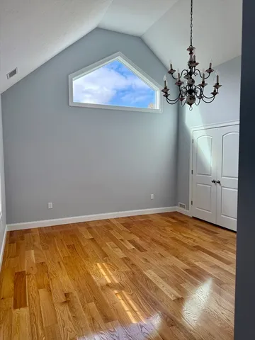 a view of a room with a chandelier fan and wooden floor