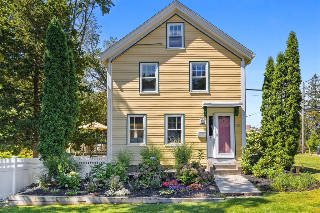 a front view of a house with a yard and potted plants