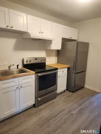 a kitchen with a white cabinets and wooden floor