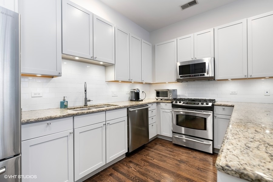 908 North Howe Street Chicago, IL 60610 - Photo 11 of 25 a kitchen with granite countertop white cabinets sink and stainless steel appliances