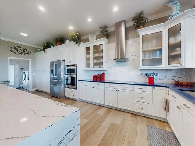 a large kitchen with stainless steel appliances kitchen island granite countertop a refrigerator and a sink