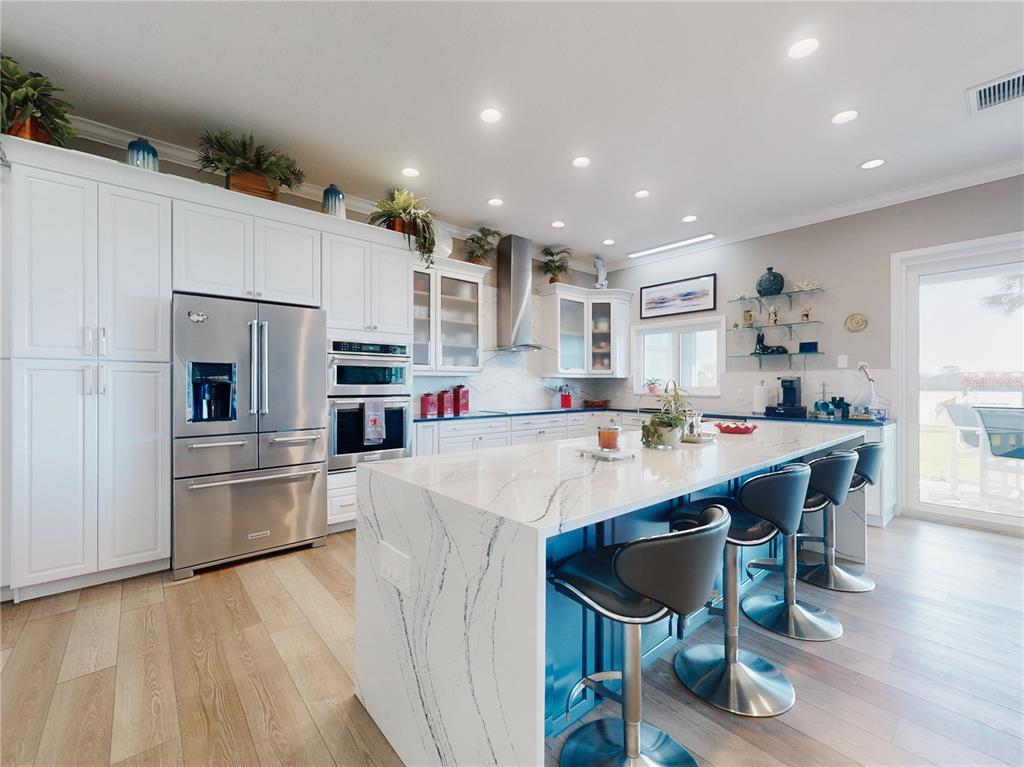 2019 South Riverside Drive Edgewater, FL 32141 - Photo 19 of 94 a kitchen with kitchen island a stove a refrigerator and a dining table with wooden floor