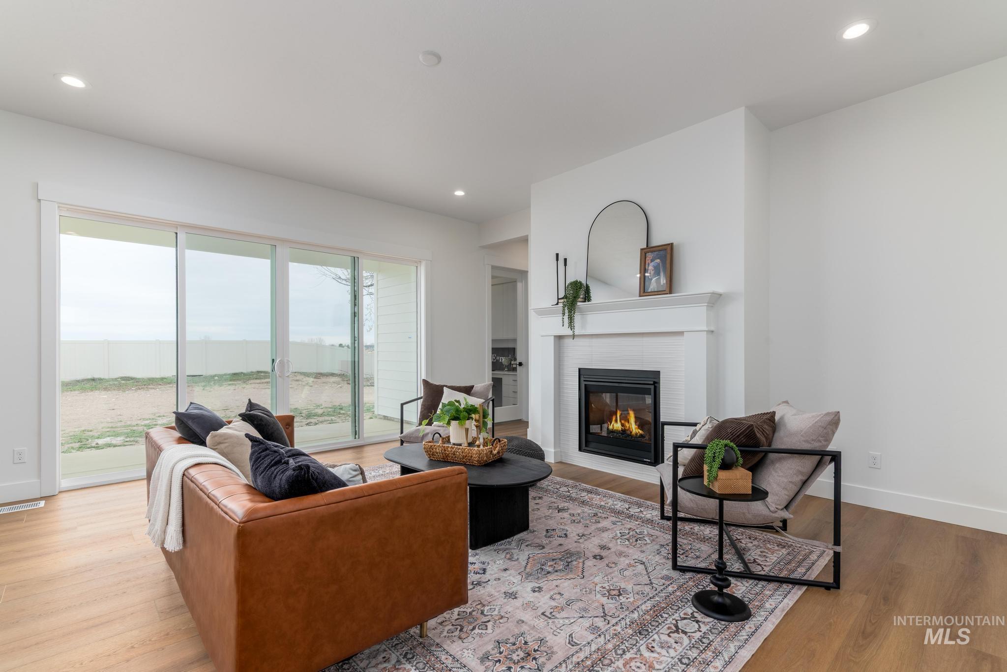 9131 West Moonglade Street Star, ID 83669 - Photo 2 of 22 Living room featuring light wood-style flooring, a glass covered fireplace, and recessed lighting