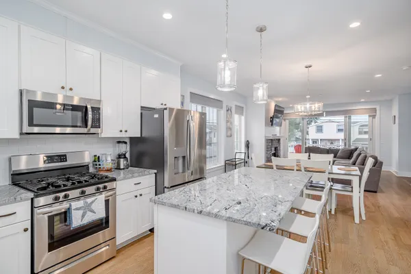 a kitchen with stainless steel appliances kitchen island granite countertop a stove a refrigerator a oven a sink with a dining table and chairs