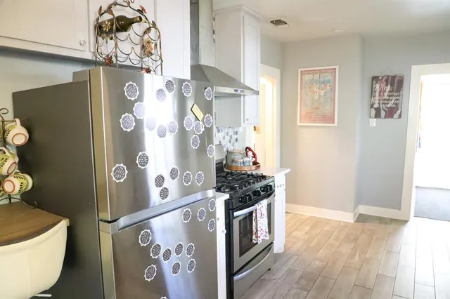 a kitchen with stainless steel appliances granite countertop a refrigerator and a stove with wooden floor